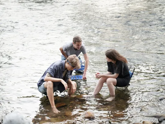 Student studying marine life in a river.