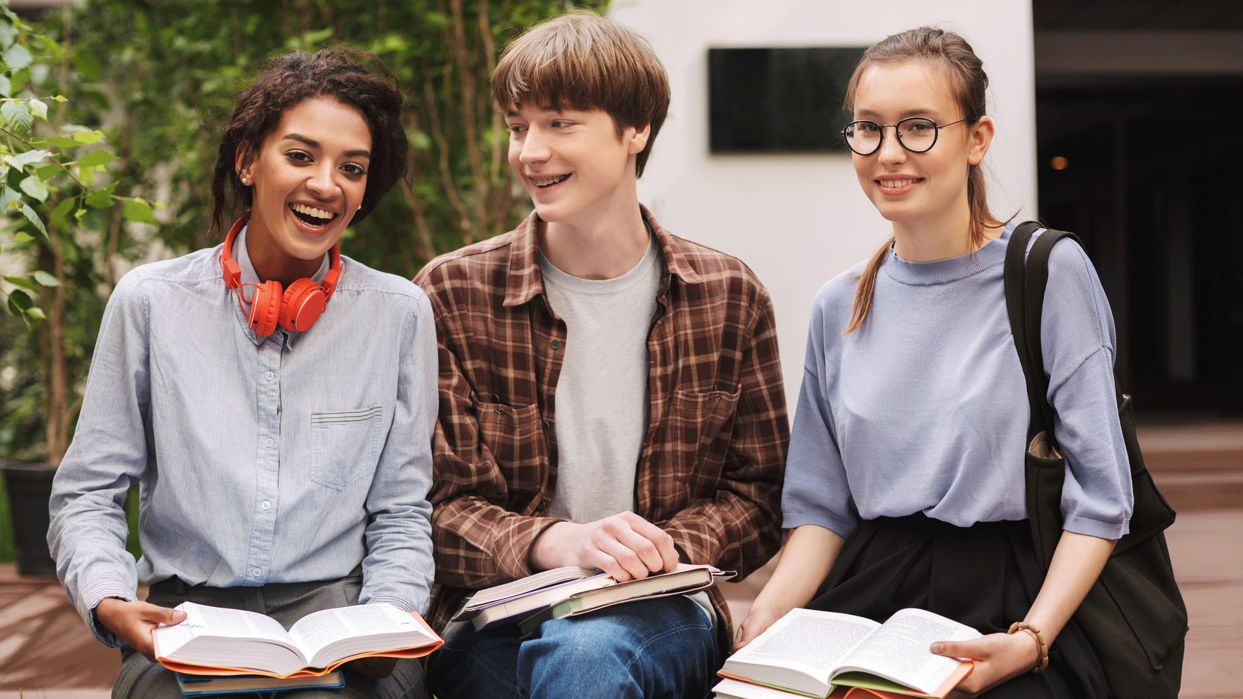 Mixed group of students sat outside laughing. 