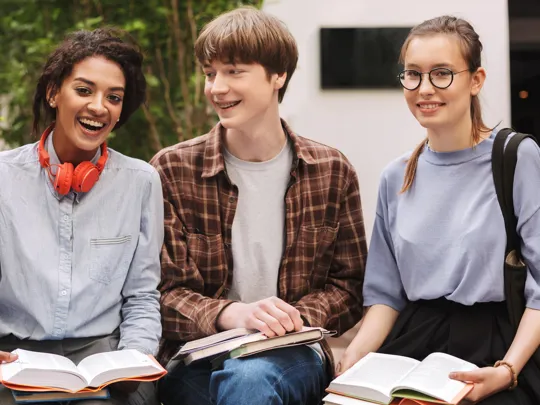 Mixed group of students sat outside laughing.