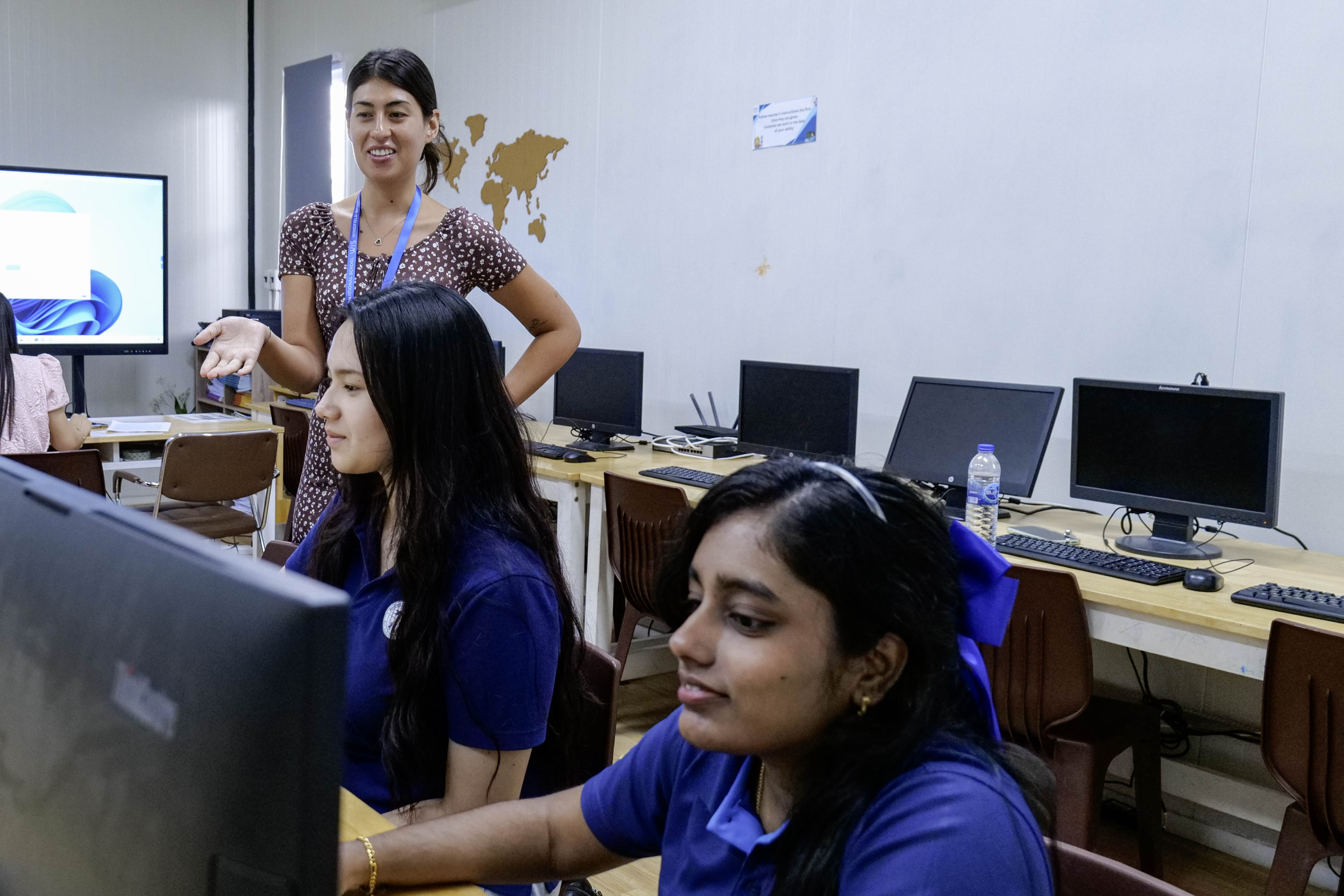 Photo of a Windfield International School teacher helping students.