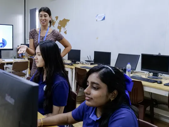 Photo of a Windfield International School teacher helping students.