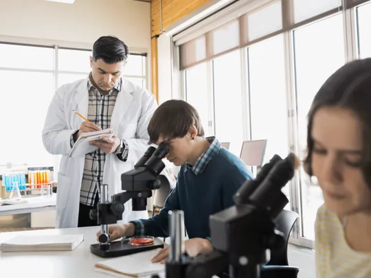 Students looking through a microscope in a science lesson.