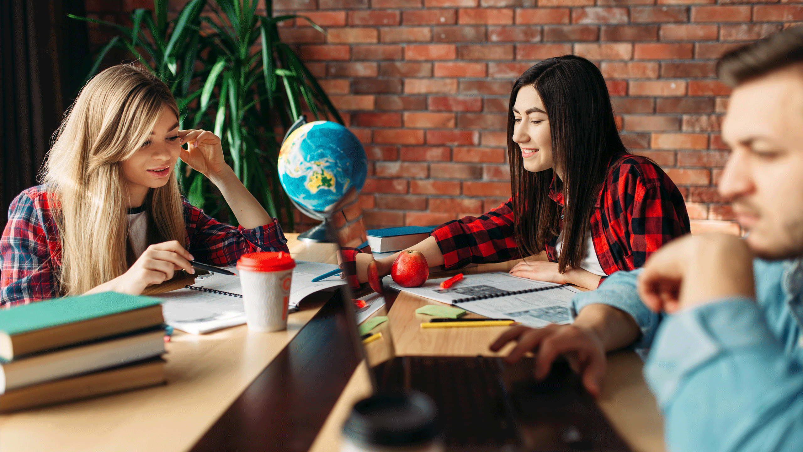 3 students stat working around a globe.