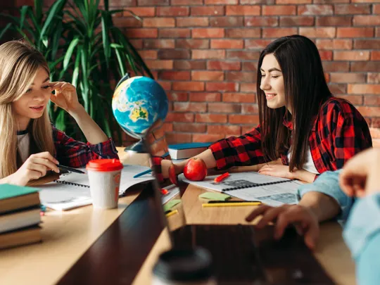 3 students stat working around a globe.