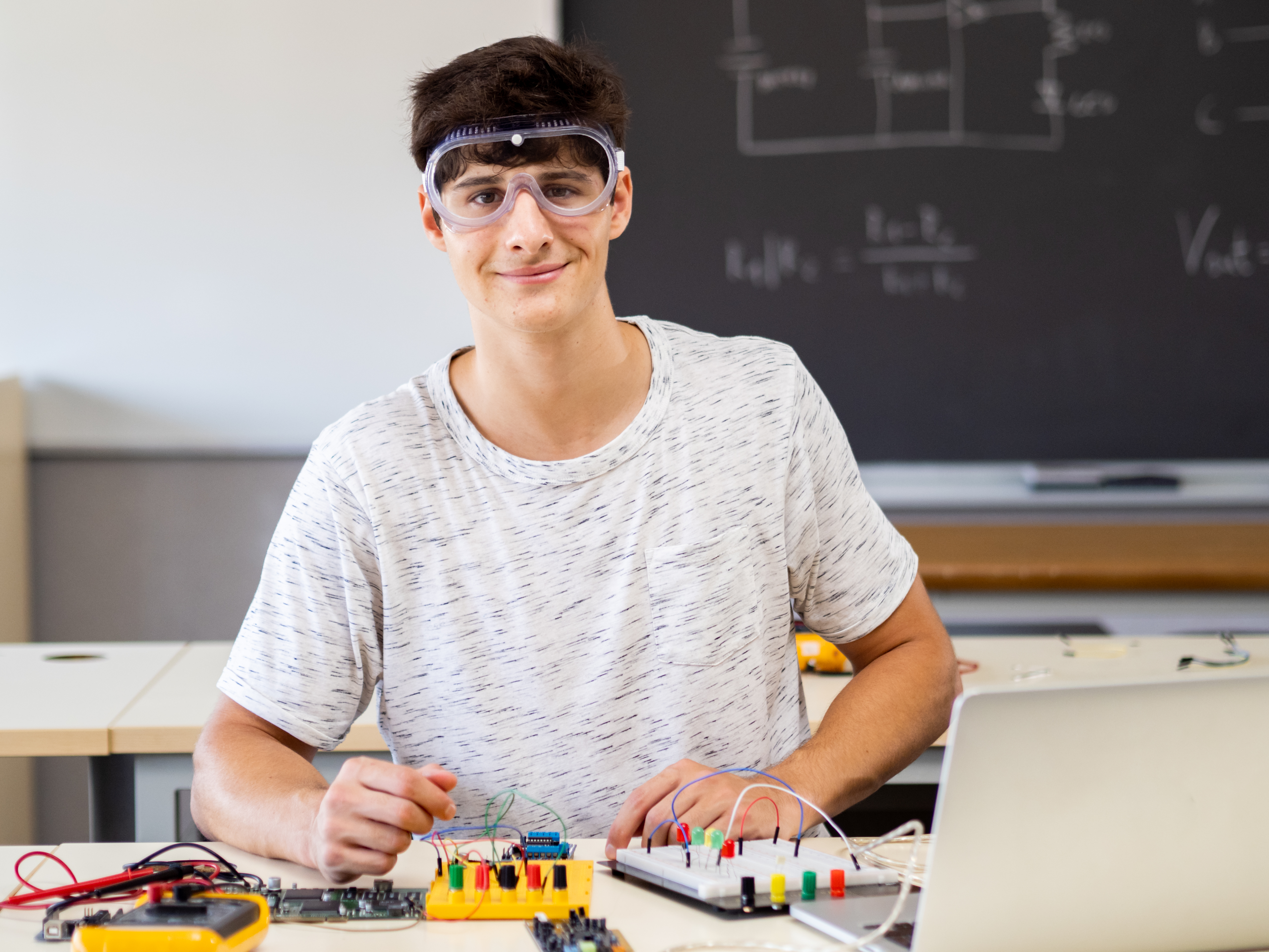 Student assembling electronic components and circuits on a desk in a physics classroom