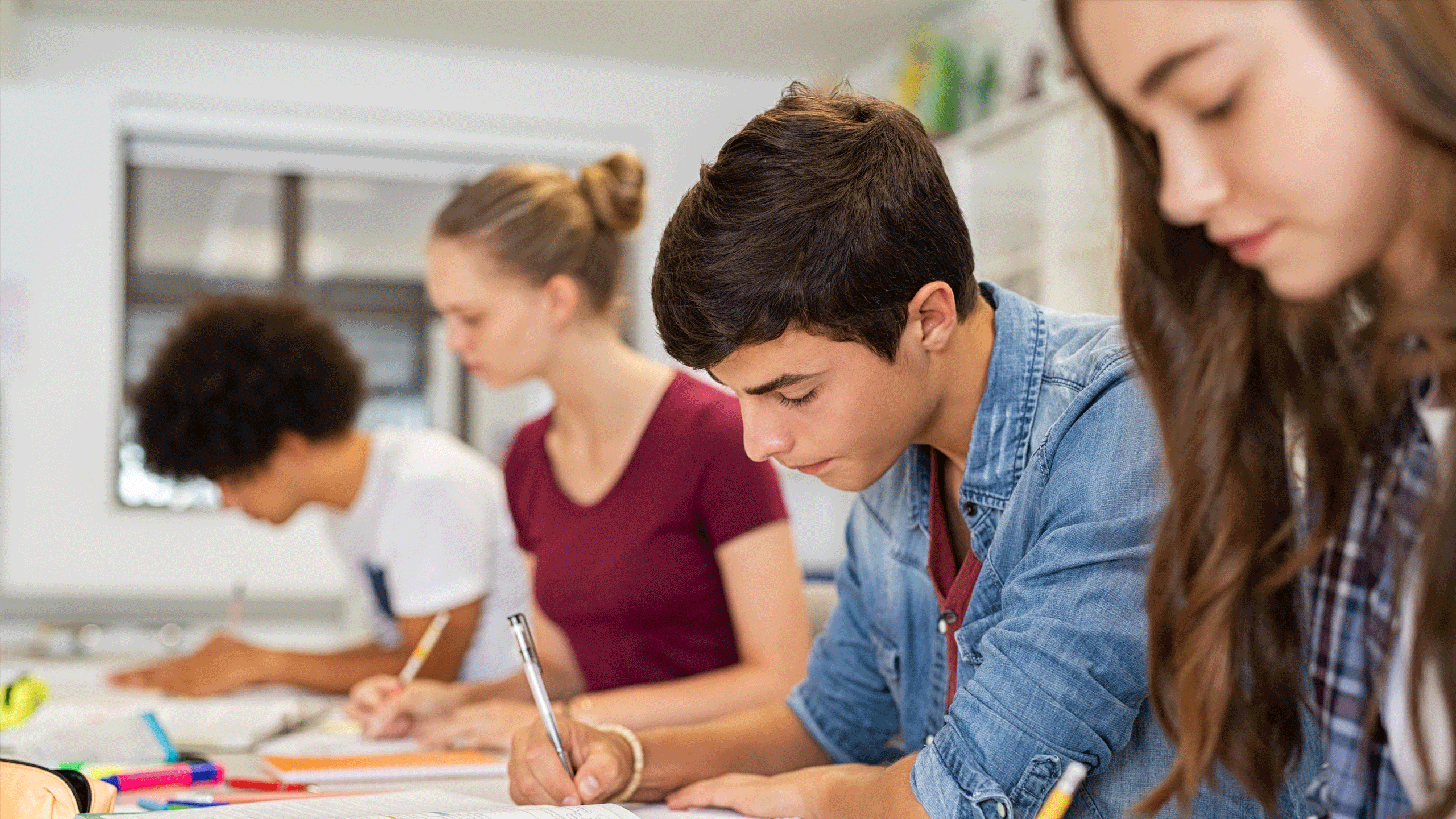 Mixed group of students writing into a text book.